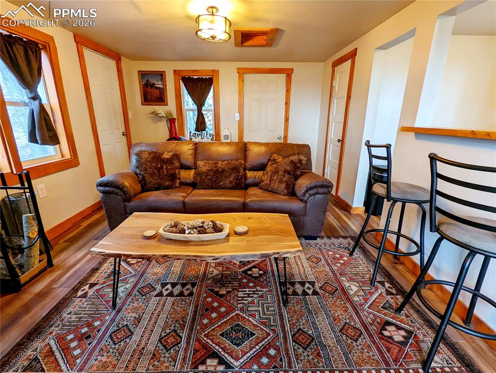 Image 12 of 21: Living area featuring wood-finish flooring, white walls with wood trim, and
