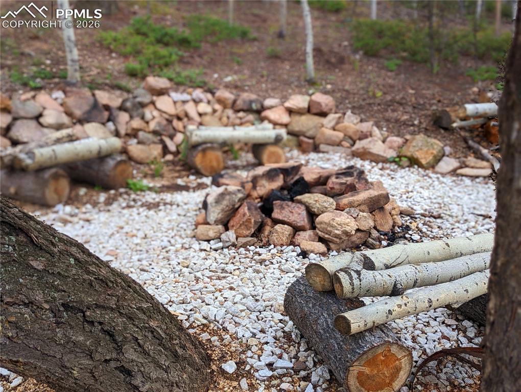 Image 4 of 21: Outdoor fire pit area featuring a stone-lined fire pit, white gravel ground