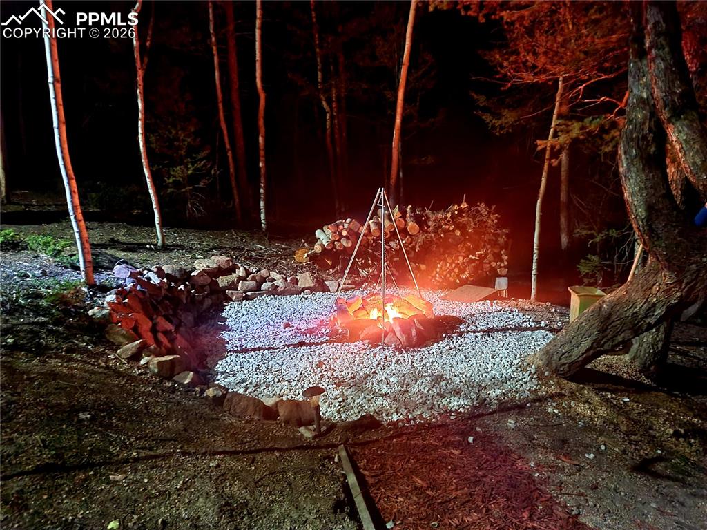 Image 5 of 21: Outdoor fire pit area featuring a gravel base, surrounding stone edging, an