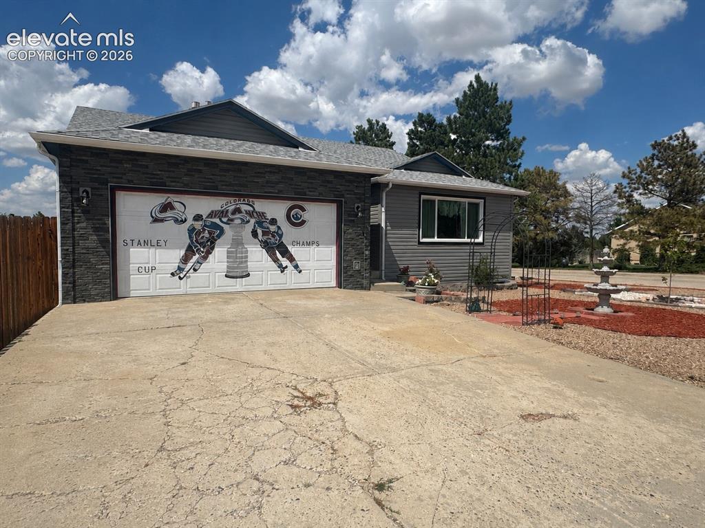 Image 1 of 20: Attached garage with stone veneer facade and graphic door