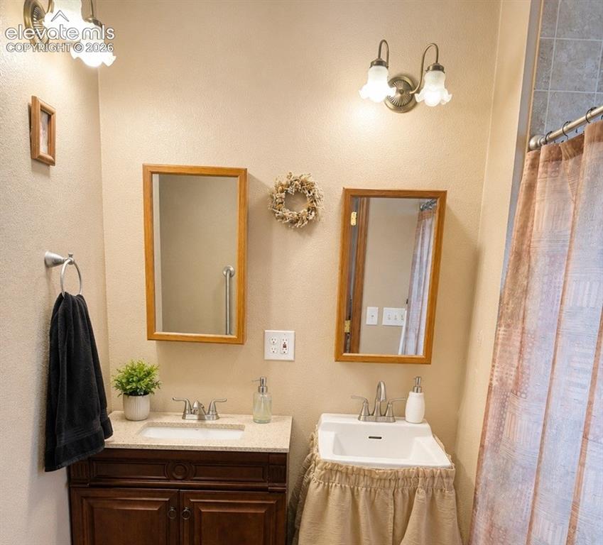 Image 12 of 20: Bathroom featuring a double vanity with a dark wood-finish cabinet and a pe