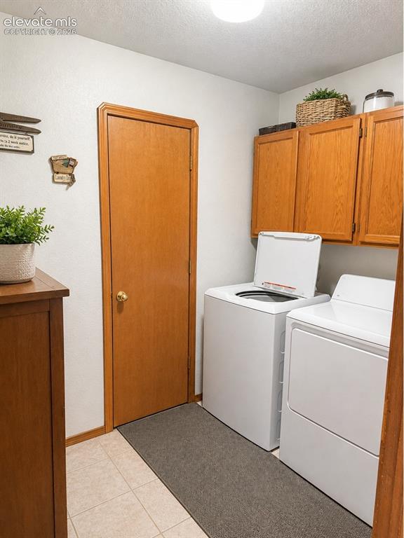 Image 16 of 20: Laundry area featuring light wood-finish cabinetry, tile flooring, and a fl