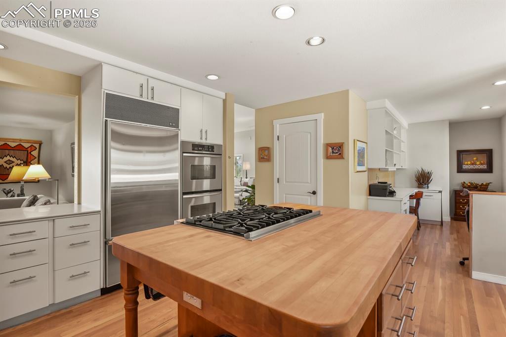 Image 18 of 50: Kitchen with light wood-type flooring, stainless steel appliances, white ca