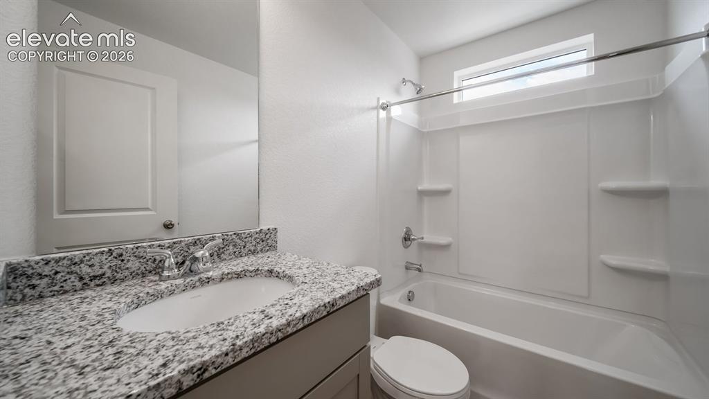 Image 10 of 36: Bathroom featuring a white vanity with a granite-style countertop and a whi