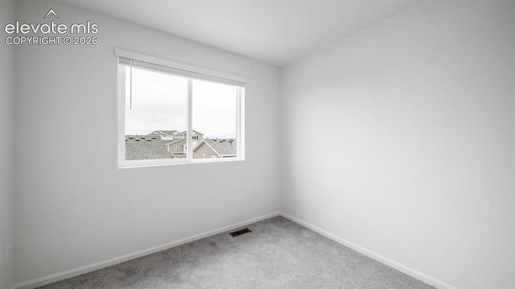 Image 14 of 36: Room with light gray carpeting, white walls, and a large window featuring w
