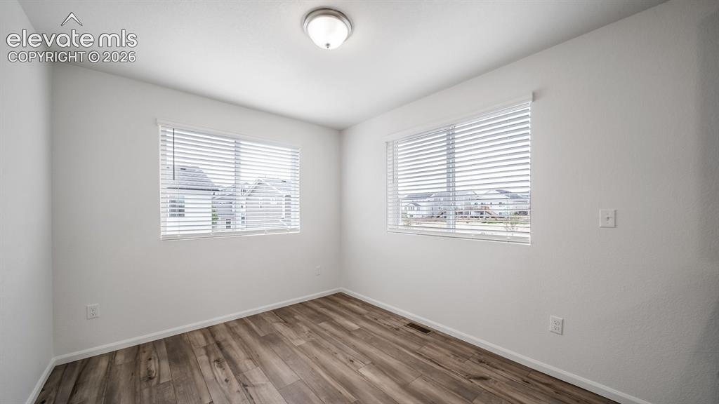 Image 15 of 36: Room featuring two windows with horizontal blinds, wood-finish flooring, wh