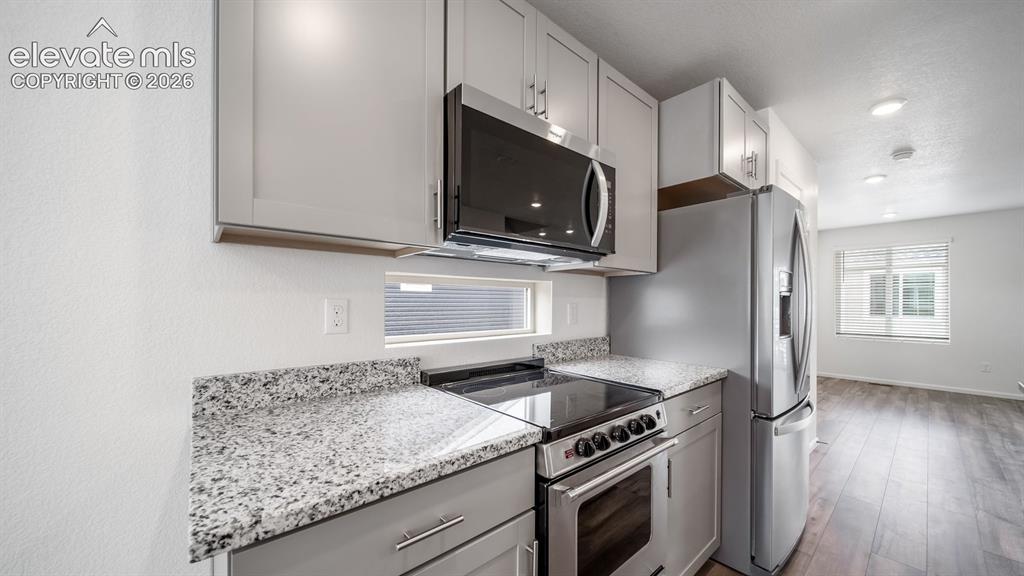 Image 20 of 36: Kitchen area featuring light gray cabinetry, speckled countertops, stainles