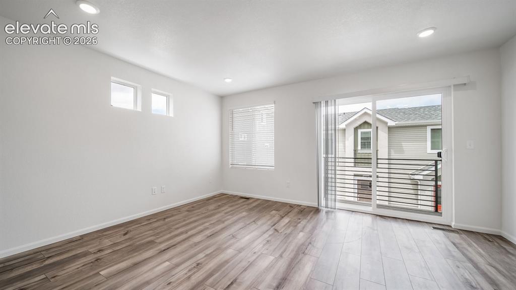 Image 28 of 36: Spacious room featuring wood-finish flooring, recessed lighting, and a slid