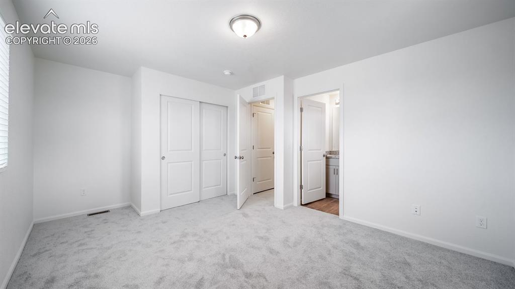 Image 32 of 36: Spacious room featuring light gray carpet flooring, white walls, a window w