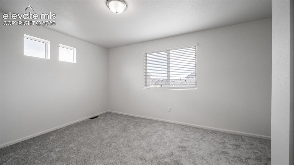 Image 33 of 36: White-painted room featuring gray carpeting, a single ceiling light fixture
