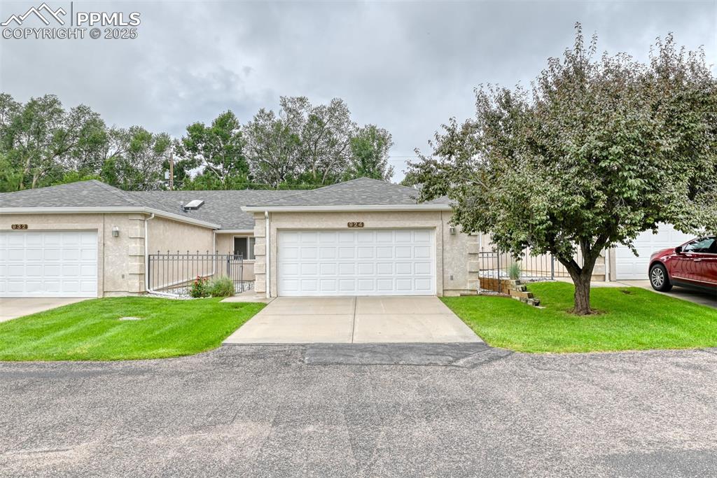 Caption: View of front of home featuring driveway, a garage, stucco siding, and roof with shingles