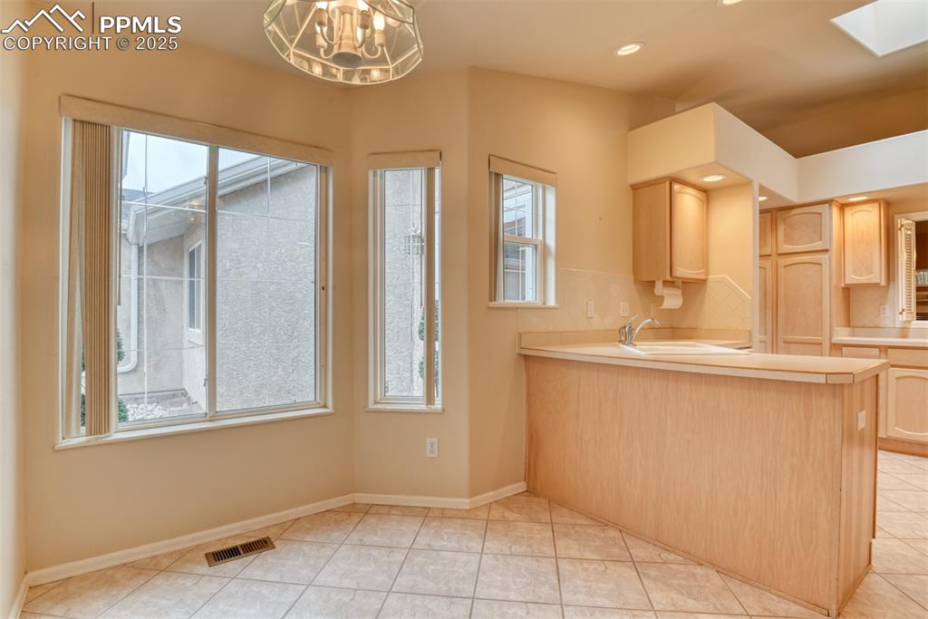 Image 12 of 37: Kitchen featuring light brown cabinetry, light countertops, a skylight, rec