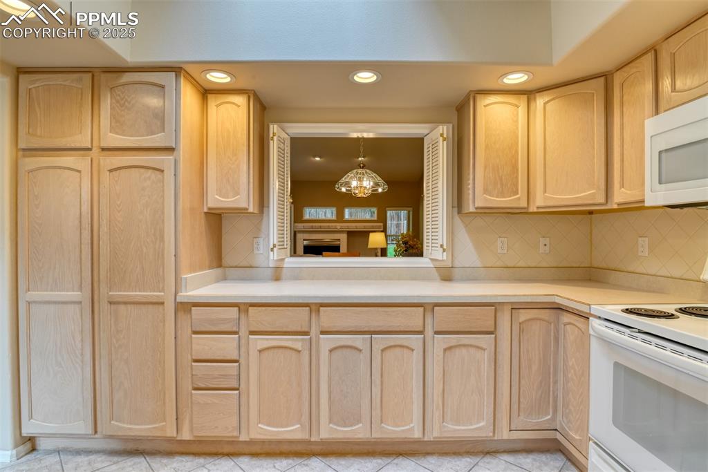 Image 13 of 37: Kitchen with light brown cabinets, white appliances, recessed lighting, dec