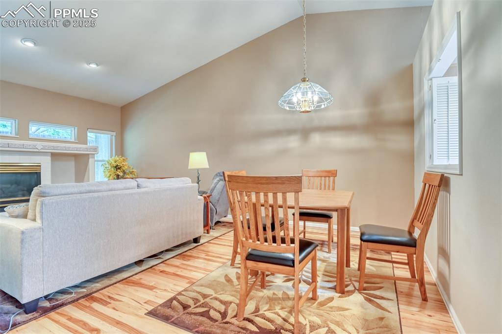 Image 14 of 37: Dining space featuring wood finished floors, a fireplace, and high vaulted