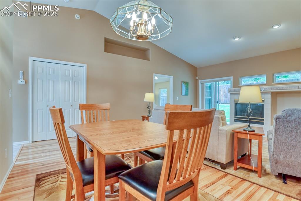 Image 17 of 37: Dining room with vaulted ceiling, light wood-style flooring, a glass covere