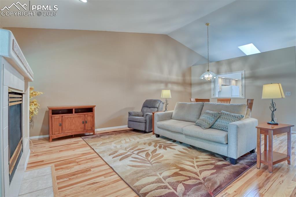 Image 20 of 37: Living room featuring a tile fireplace, light wood-style flooring, a skylig