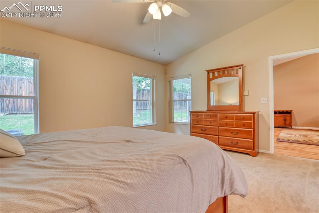 Image 25 of 37: Carpeted bedroom with ceiling fan and lofted ceiling