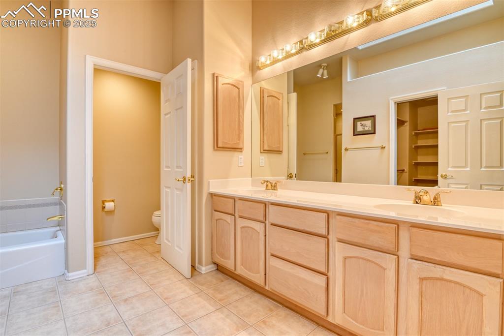 Image 26 of 37: Full bathroom with double vanity, light tile patterned floors, a garden tub
