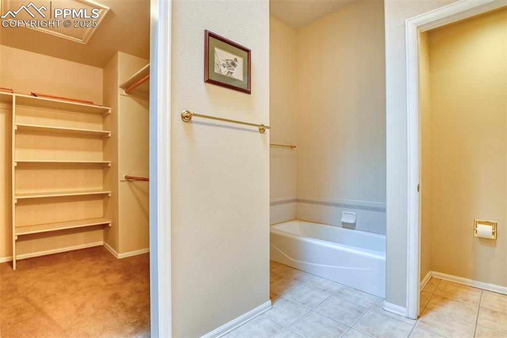 Image 27 of 37: Bathroom featuring a garden tub, light tile patterned flooring, and a close