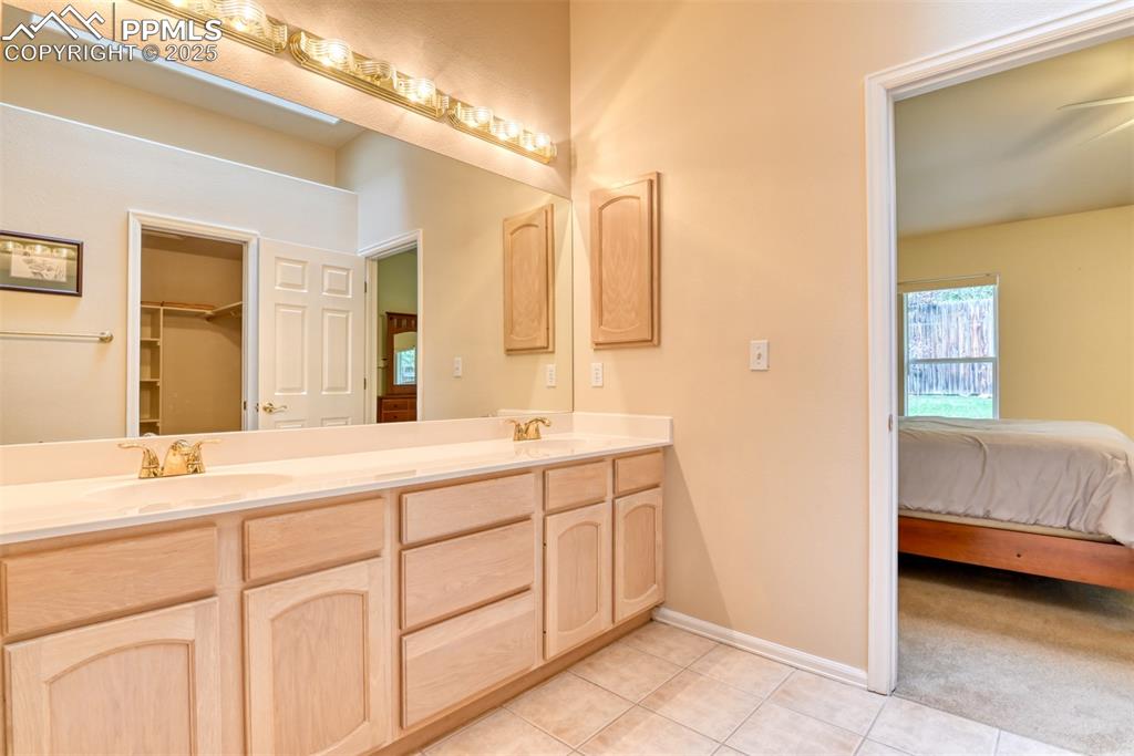 Image 28 of 37: Ensuite bathroom with double vanity, light tile patterned flooring, and a w