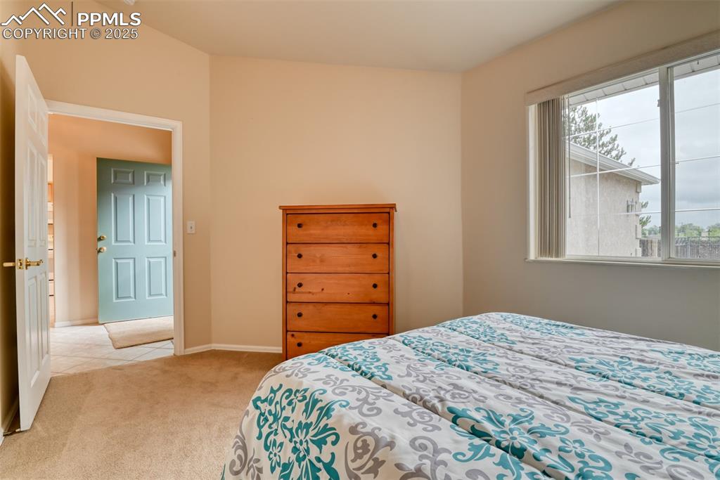 Image 32 of 37: Bedroom featuring light colored carpet and light tile patterned floors