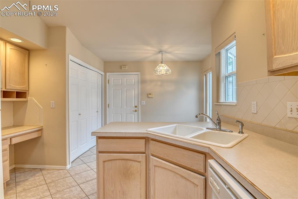 Image 5 of 37: Kitchen with light brown cabinets, built in study area, and light counterto