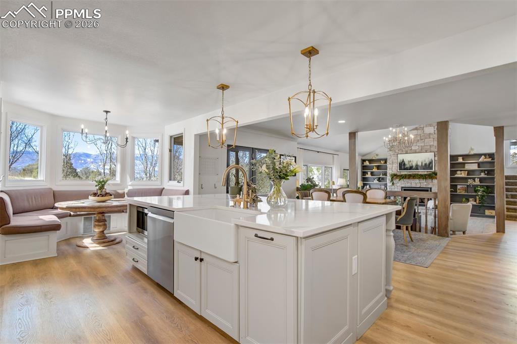 Image 13 of 49: Kitchen with hanging lights, open floor plan, an island with sink, and vaul
