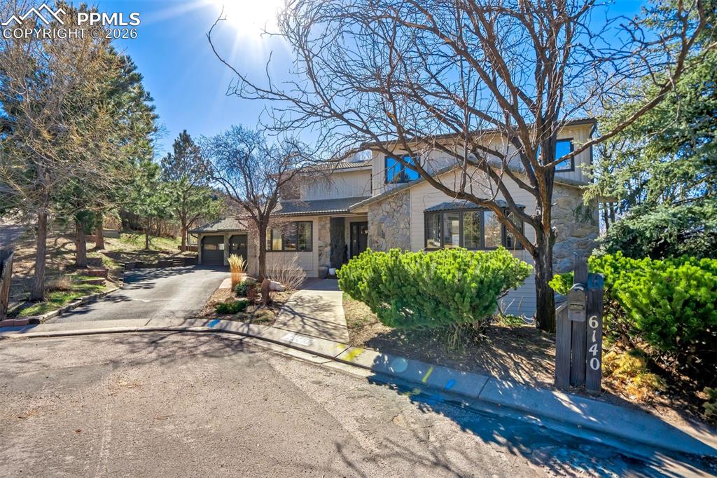 Image 2 of 49: Traditional-style house featuring stone siding, driveway, and an attached g