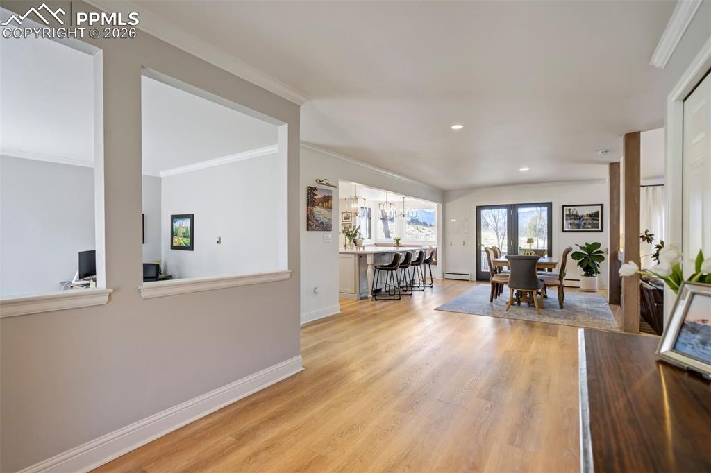 Image 21 of 49: Living area with light wood-type flooring, ornamental molding, a baseboard 