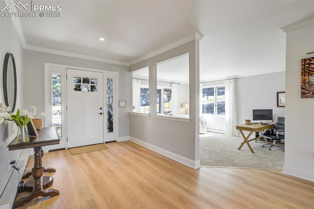Image 22 of 49: Foyer with ornamental molding and light wood-style flooring