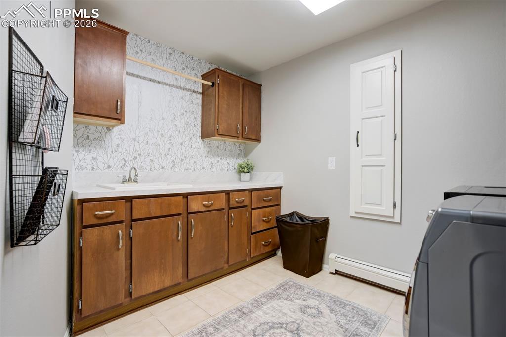 Image 35 of 49: Main Level Laundry room with a baseboard heating unit, cabinet space, and w