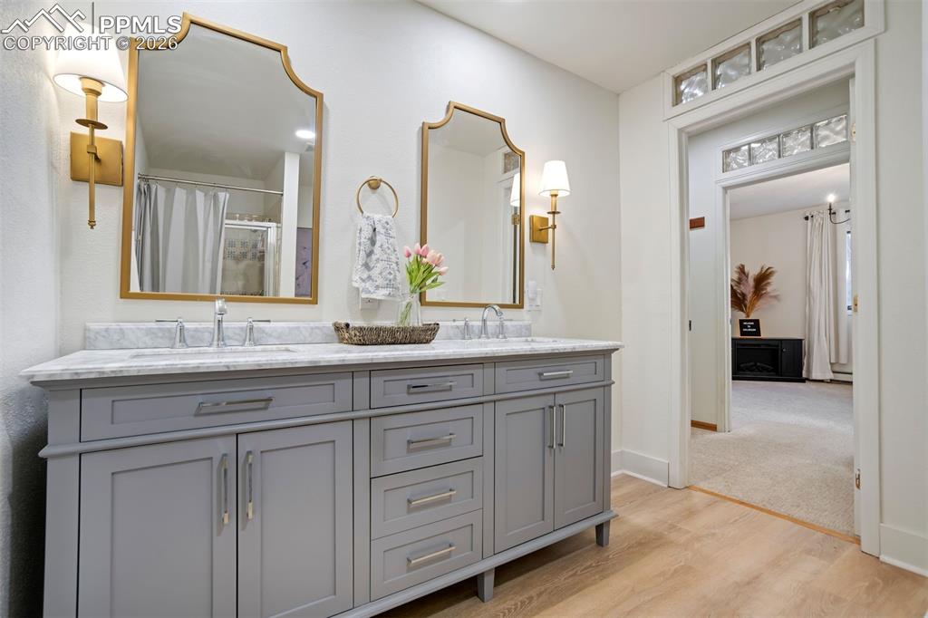 Image 38 of 49: Basement Bathroom featuring double vanity, a shower, and light wood-style f