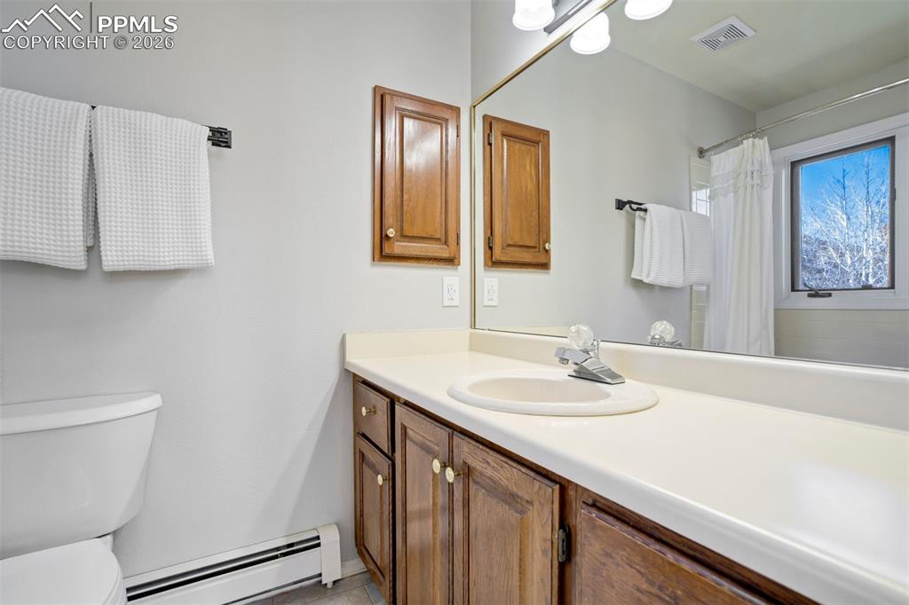 Image 40 of 49: Full bath with a baseboard radiator, vanity, and curtained shower
