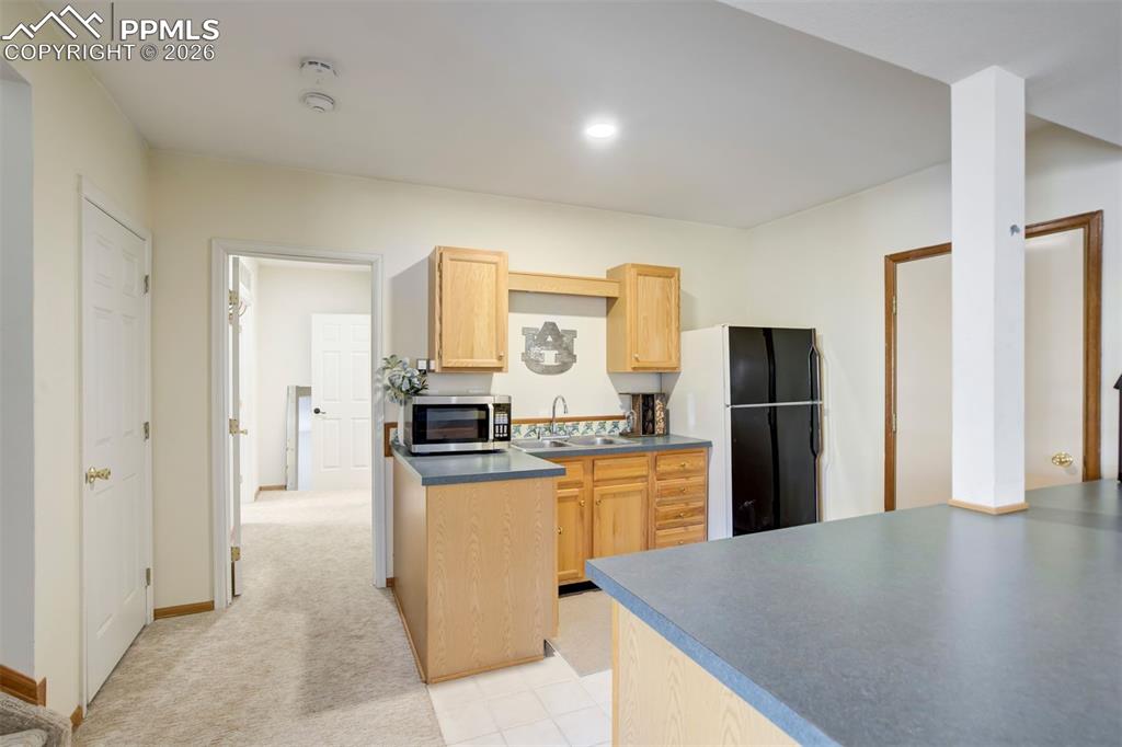 Image 41 of 49: Basement mini kitchen, full size refrigerator.  Ready for a remodel. 