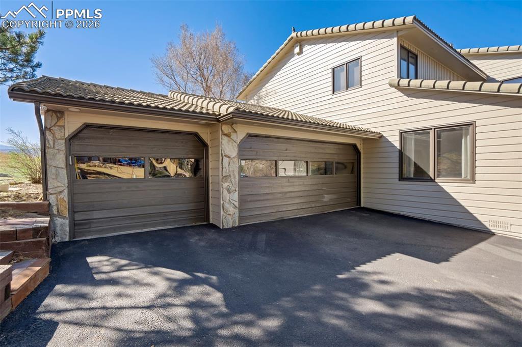 Image 47 of 49: View of front of property with a tiled roof, asphalt driveway, an attached 