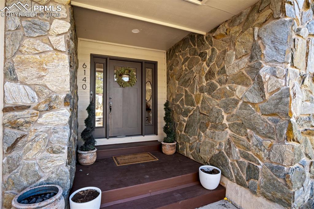 Image 6 of 49: Property entrance with stone siding and a porch