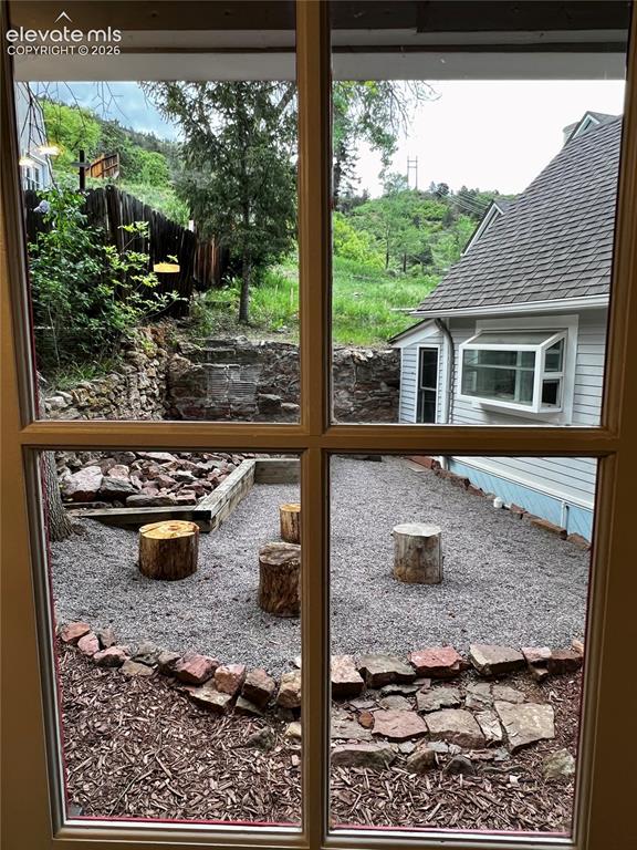 Image 28 of 45: Upper Apt: View from kitchen to the patio with fire pit and picnic table