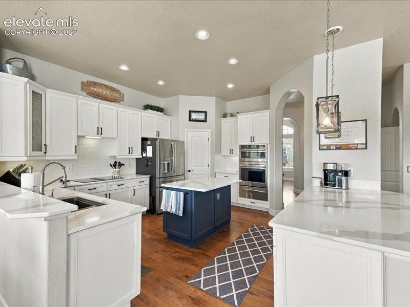 Image 11 of 50: White shaker cabinetry, stainless steel appliances, wood-finish flooring, r