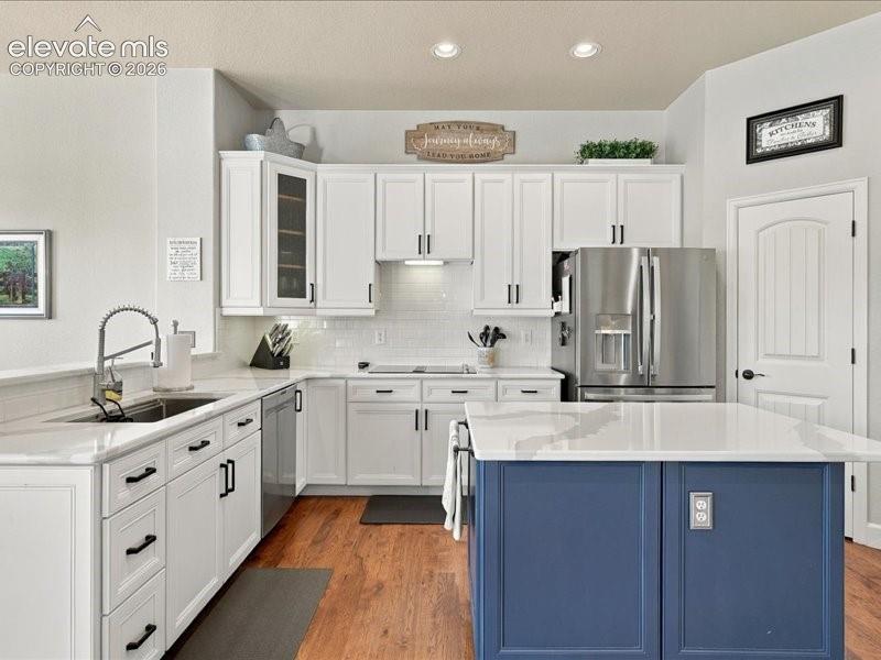 Image 13 of 50: Kitchen featuring white shaker-style cabinetry, a blue island with a white