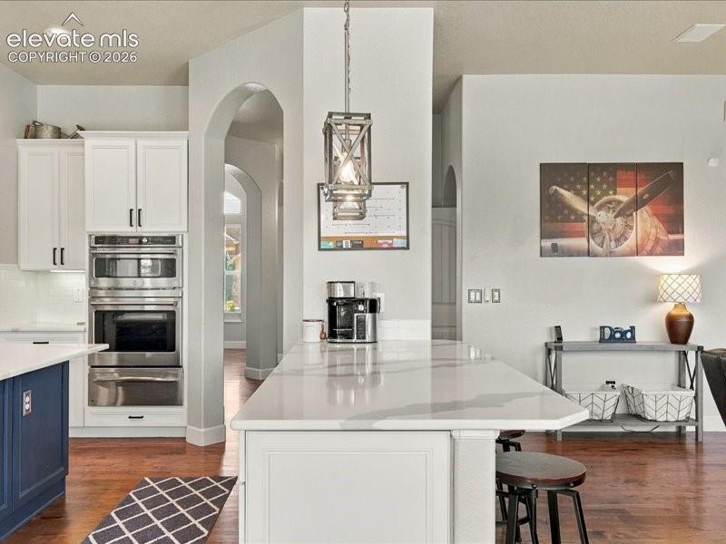 Image 17 of 50: Kitchen featuring a spacious island with a light-toned countertop, white ca