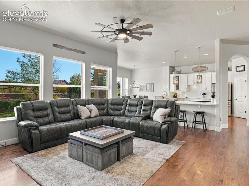 Image 19 of 50: Open-concept living space featuring a sectional reclining sofa, wood-finish