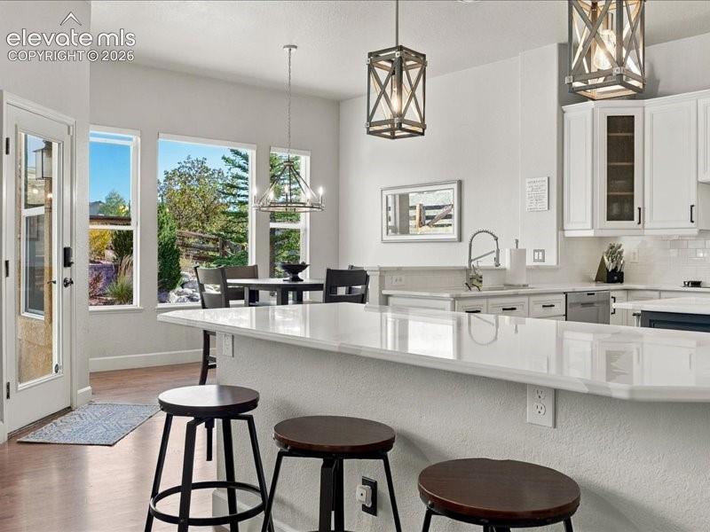 Image 2 of 50: Kitchen featuring wood-finish flooring, white cabinetry, a kitchen island w