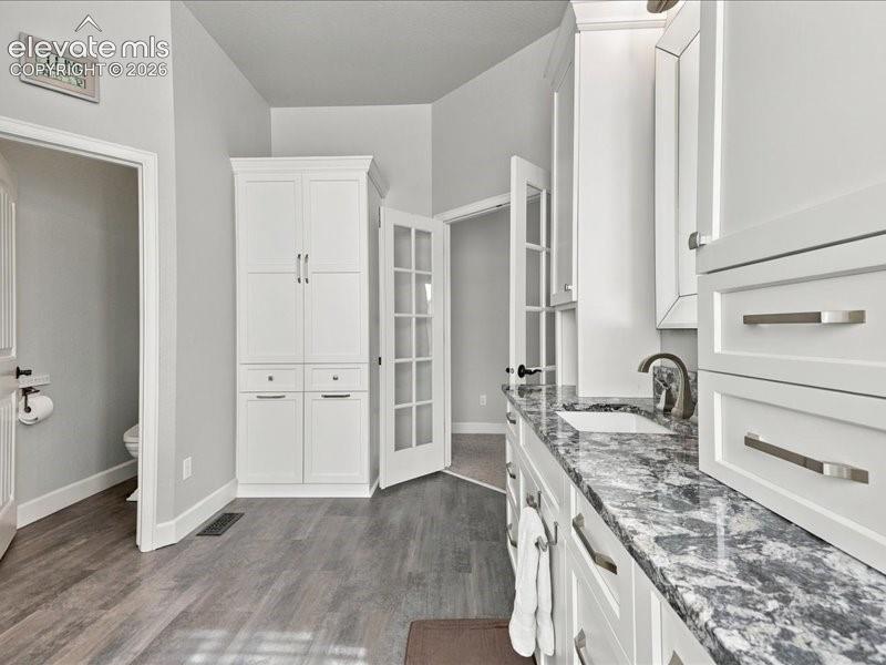 Image 27 of 50: White cabinetry with brushed nickel hardware, expansive countertop with an 