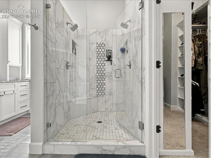 Image 28 of 50: Spacious walk-in shower with glass enclosure, dual shower heads, integrated