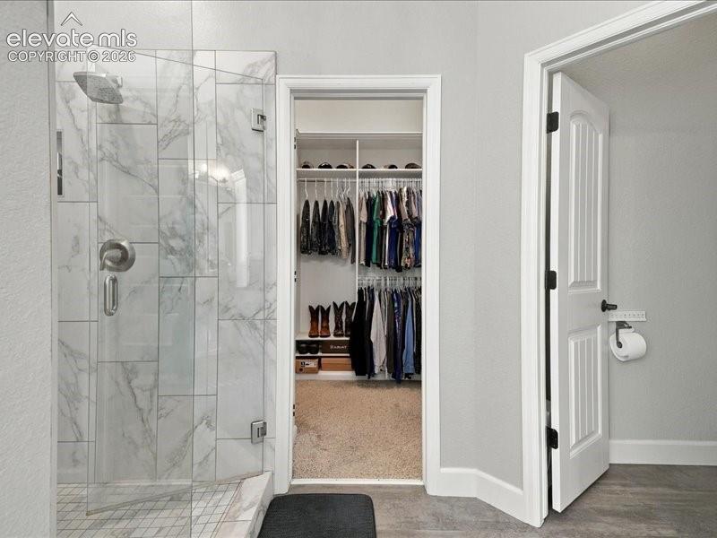 Image 29 of 50: Walk-in shower with clear glass enclosure and marble-look tile surround