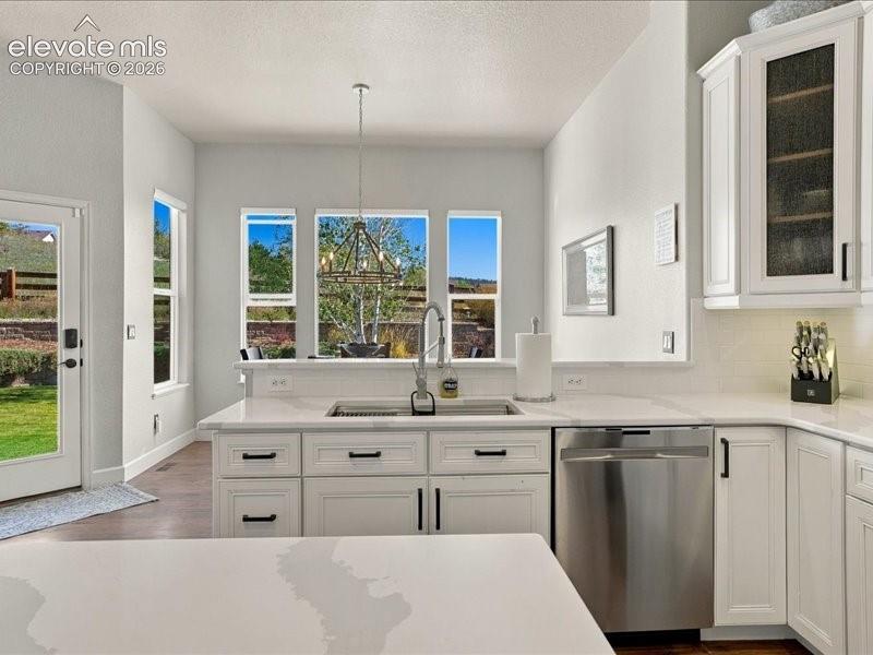 Image 3 of 50: Bright kitchen featuring white cabinetry with black hardware, quartz counte