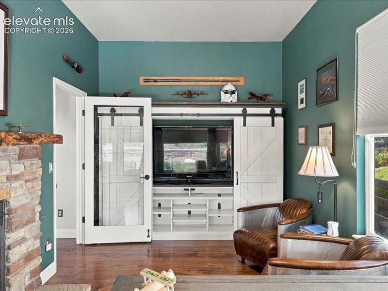Image 36 of 50: Built-in entertainment center with sliding barn doors, wood-finish flooring