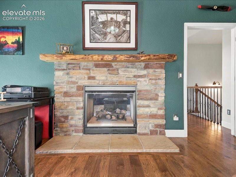 Image 37 of 50: Stone-clad fireplace with a natural wood mantel