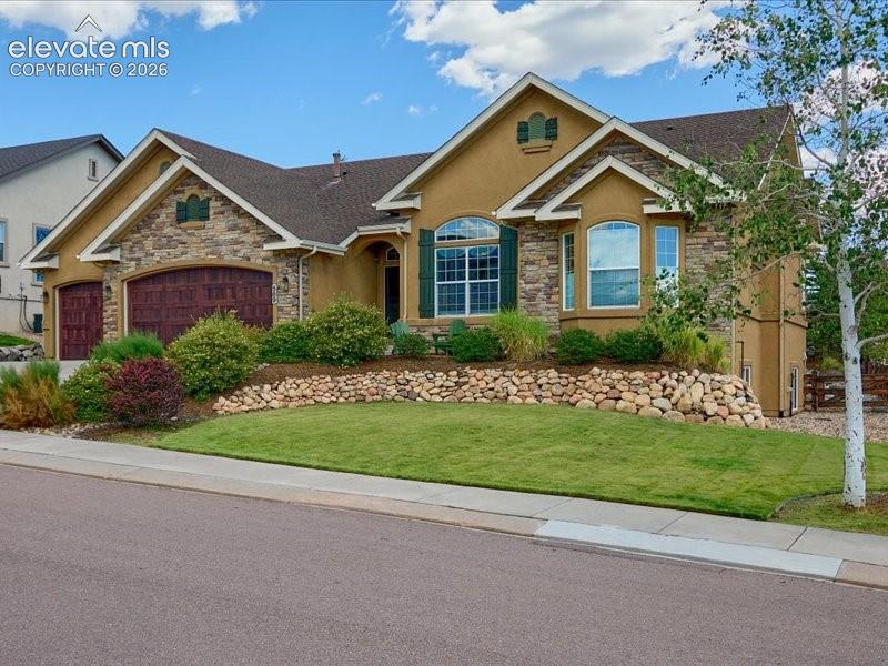 Image 38 of 50: Elegant single-story residence featuring a stucco and stone exterior with a
