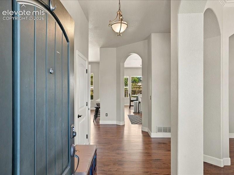 Image 9 of 50: Entryway featuring a paneled front door, wood-finish flooring, arched doorw
